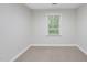 A bright, carpeted bedroom features neutral walls, white trim, and a window with a serene view of the outdoors at 103 Oxford Cir, Knightdale, NC 27545