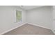 A bright, carpeted bedroom features neutral walls, white trim, and a window with a serene view of the outdoors at 103 Oxford Cir, Knightdale, NC 27545