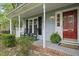 Inviting front porch with rocking chairs, potted plants, and a red front door at 103 Oxford Cir, Knightdale, NC 27545