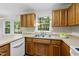 Bright kitchen featuring a window, wood cabinets, stainless steel sink and white appliances at 103 Oxford Cir, Knightdale, NC 27545