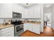 Charming kitchen with white cabinets, granite countertops, stainless steel appliances, and hardwood flooring, offering an inviting space at 104 S Crabtree Knl, Chapel Hill, NC 27514