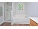 Bright bathroom featuring a large soaking tub with shower and a window for natural light at 1056 Evening Shade Ave, Rolesville, NC 27571