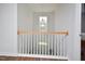 Bright hallway featuring wood floors, wood railing, and a decorative light fixture at 1056 Evening Shade Ave, Rolesville, NC 27571