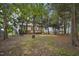 Tranquil backyard view highlighting a wooden deck and a home framed by tall, mature trees and lush greenery at 107 Governors House Dr, Morrisville, NC 27560