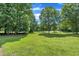 Expansive backyard featuring mature trees and lush green grass, ideal for outdoor activities at 113 Feezor Ct, Clayton, NC 27527