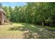 Lush backyard with mature trees and landscaping featuring a screened-in porch at 120 Tanager Farms Dr, Youngsville, NC 27596