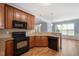 Open kitchen has wooden cabinets, sleek black appliances, and a view to the dining area at 120 Tanager Farms Dr, Youngsville, NC 27596