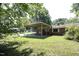 Backyard with lawn space, covered parking area, and brick facade of the home at 1209 Landon St, Durham, NC 27703