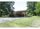 Back of property featuring a brick facade, chimney, driveway, and covered parking area at 1209 Landon St, Durham, NC 27703