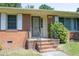 Close-up of the brick front porch with a metal railing and painted front door at 1209 Landon St, Durham, NC 27703
