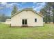 Rear view of the house with light yellow siding, slider, and red brick chimney at 1398 Tarboro Rd, Youngsville, NC 27596