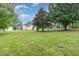 Large lot with mature trees and green grass around the yellow siding house at 1398 Tarboro Rd, Youngsville, NC 27596