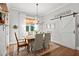 Elegant dining room with chandelier, farmhouse door, hardwood floors, and natural light at 1412 Wakefield Farm Rd, Zebulon, NC 27597