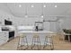Bright kitchen boasts stainless appliances, quartz countertops, white cabinets, a large island, and three bar stools at 154 Buckaroo Dr, Louisburg, NC 27549