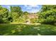 Grassy backyard with steps leading to home's back, surrounded by mature trees at 1641 Regency Dr, Burlington, NC 27215