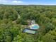 Aerial view of a luxurious community pool, tennis court, and clubhouse surrounded by lush greenery at 1702 Mcrae Pl, Hillsborough, NC 27278
