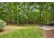 A spacious backyard showcasing a patio area, lush green lawn, and picturesque wooded scenery at 1702 Mcrae Pl, Hillsborough, NC 27278