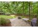 Backyard featuring a circular brick patio with a fire pit, grilling area, and beautiful mature trees at 1702 Mcrae Pl, Hillsborough, NC 27278