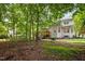 Scenic backyard featuring a patio, deck, mature trees, and lush greenery, creating a private oasis at 1702 Mcrae Pl, Hillsborough, NC 27278