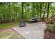 A secluded patio in a wooded backyard, featuring a fire pit and cooking area next to the deck at 1702 Mcrae Pl, Hillsborough, NC 27278