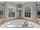 Bright bathroom featuring a large corner soaking tub with stylish fixtures, with natural light from the nearby windows at 1702 Mcrae Pl, Hillsborough, NC 27278