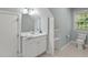 Bathroom with a white single sink vanity, toilet, and built in storage next to a window at 1702 Mcrae Pl, Hillsborough, NC 27278