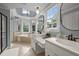 This luxury bathroom offers dual vanities, a soaking tub, and a chandelier, complemented by ample natural light at 1702 Mcrae Pl, Hillsborough, NC 27278
