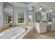 This luxury bathroom features a soaking tub, dual vanities, and natural light from the expansive windows at 1702 Mcrae Pl, Hillsborough, NC 27278