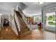 Open foyer with staircase, hardwood floors, and a glimpse of the living room and entryway at 1702 Mcrae Pl, Hillsborough, NC 27278