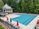 Large community swimming pool surrounded by lounge chairs, umbrellas, and a pool house providing a resort-like feel at 1702 Mcrae Pl, Hillsborough, NC 27278