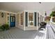 Inviting covered porch with blue door, large windows with dark shutters, and comfortable seating at 1702 Mcrae Pl, Hillsborough, NC 27278