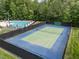 Aerial shot of tennis court, next to swimming pool, enclosed by a black fence and surrounded by greenery at 1702 Mcrae Pl, Hillsborough, NC 27278