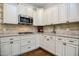 A close up of a stylish kitchen with white cabinets, granite countertops, and stainless steel appliances at 18 Heathgreen Dr, Clayton, NC 27527