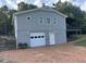Rear exterior view showcasing a spacious gray home with an attached garage and brick driveway at 197 Country Routt Brown Rd, Pittsboro, NC 27312