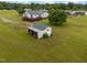 Aerial showcasing a home, large shed, and wood storage with a green metal roof on a grassy property at 1993 Lucy Garrett Rd, Roxboro, NC 27574