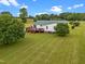 Expansive backyard with a green lawn, deck, and mature trees create a serene outdoor oasis at 1993 Lucy Garrett Rd, Roxboro, NC 27574