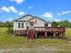 Charming single-story home featuring a front deck, American flag, vinyl siding, and manicured landscaping at 1993 Lucy Garrett Rd, Roxboro, NC 27574