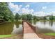 Scenic lake view featuring a wooden pier, gazebo, and surrounding trees under a partly cloudy sky at 200 Vintage Hill Cir, Apex, NC 27539