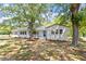 Charming white brick home with a metal roof, blue front door, and mature trees shading the manicured front yard at 2003 Broadway Rd, Sanford, NC 27332