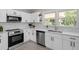Modern kitchen with stainless steel appliances, white cabinets, and a window overlooking the backyard at 2003 Broadway Rd, Sanford, NC 27332