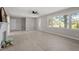 Bright, neutral living room featuring large windows, wood-look floors, a ceiling fan, and a painted brick fireplace at 2003 Broadway Rd, Sanford, NC 27332