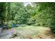 A spacious backyard with green grass, mature trees, and a cozy patio area with rocking chairs at 2236 The Cir, Raleigh, NC 27608