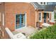 Exterior shot of a home's patio with blue French doors, brick accents, and lush greenery at 2236 The Cir, Raleigh, NC 27608