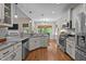 Bright kitchen featuring white cabinetry, stainless steel appliances, granite countertops, and hardwood flooring at 230 Paddy Ln, Youngsville, NC 27596