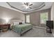 Spacious bedroom featuring a tray ceiling, neutral color scheme, carpet flooring, and natural lighting at 230 Paddy Ln, Youngsville, NC 27596