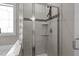 Shower featuring gray tiling, glass doors, a built-in shelf, and decorative accent tiling at 230 Paddy Ln, Youngsville, NC 27596