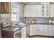 Bright kitchen boasts white cabinetry, mosaic backsplash, stainless appliances, and black granite countertops at 2616 Kirk Rd, Durham, NC 27705