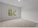 Bright bedroom with a large window overlooking the landscape, neutral walls, and carpet at 3020 Mavisbank Cir, Apex, NC 27502