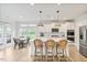 Bright open kitchen with white cabinets, island with seating, stainless appliances, and wood-look flooring at 304 Avery Glenn Way, Fuquay Varina, NC 27526