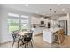Sun-filled kitchen with white cabinets, stainless appliances, island, and dining area overlooking the backyard at 304 Avery Glenn Way, Fuquay Varina, NC 27526